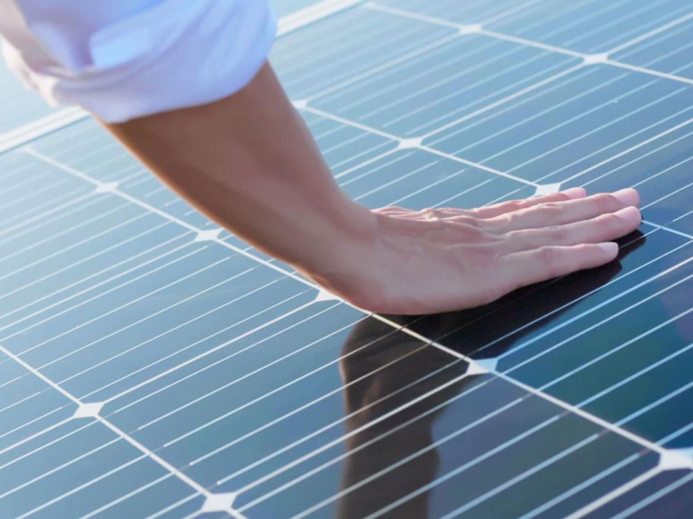 Fotovoltaikus paneleket megérintő kéz. 