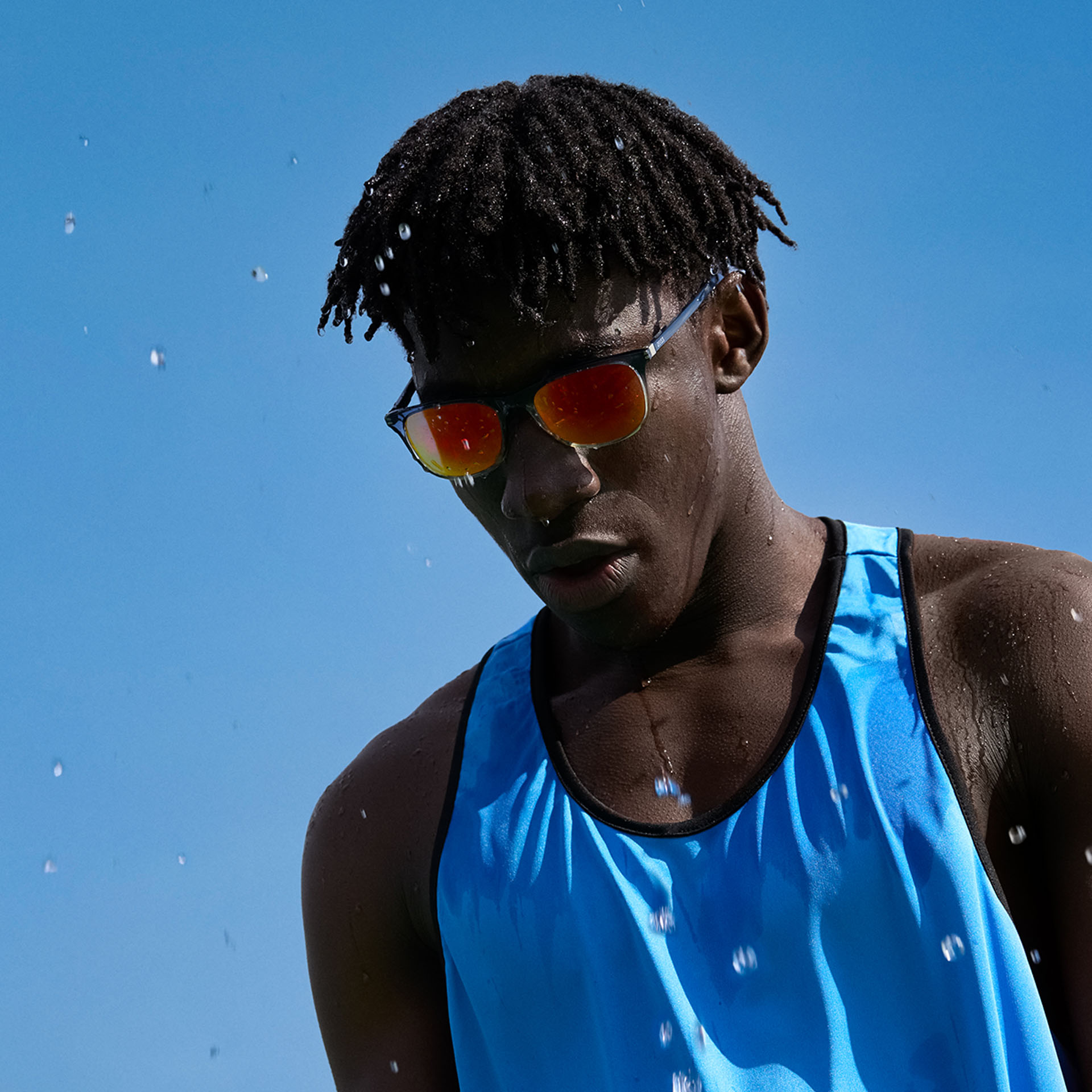 ZEISS Performance barna-narancs árnyalatú napszemüveglencsét viselő, fiatal sportoló férfi a kék ég előtt.