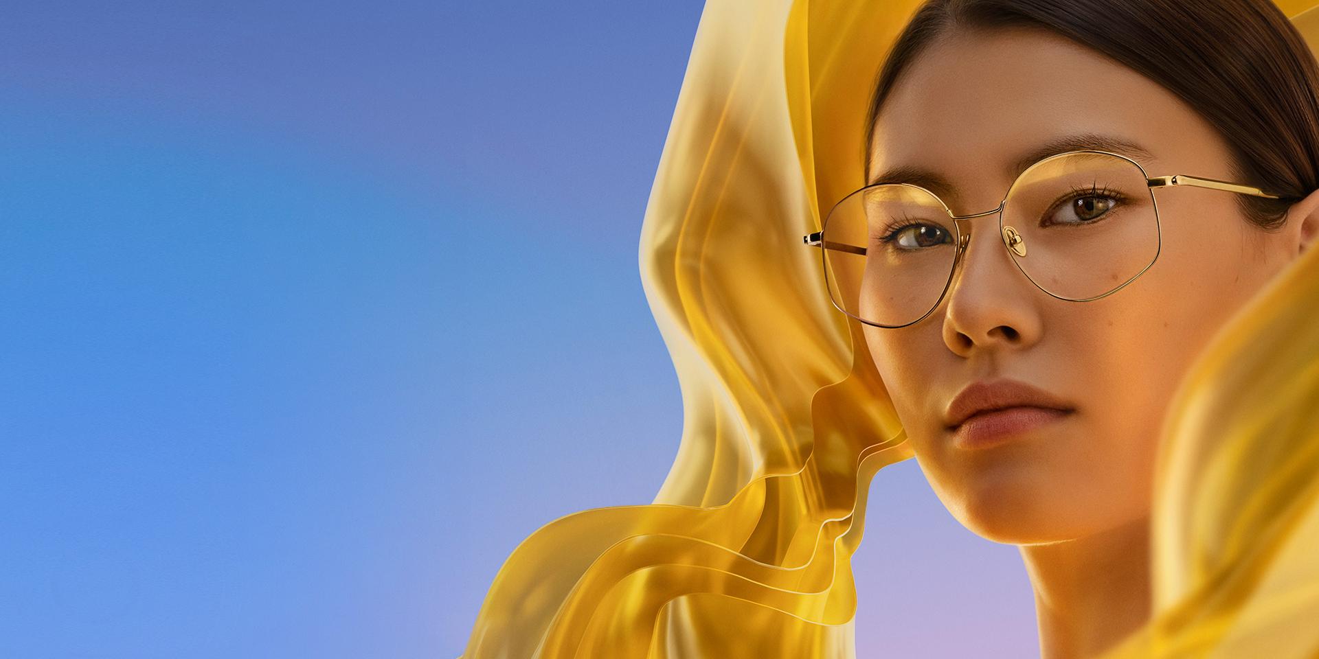 Egy nő, aki ZEISS DuraVision Gold UV bevonatú átlátszó szemüveglencsét visel, amelyen halvány, de jól észlelhető aranyszínű visszatükröződés látszik.