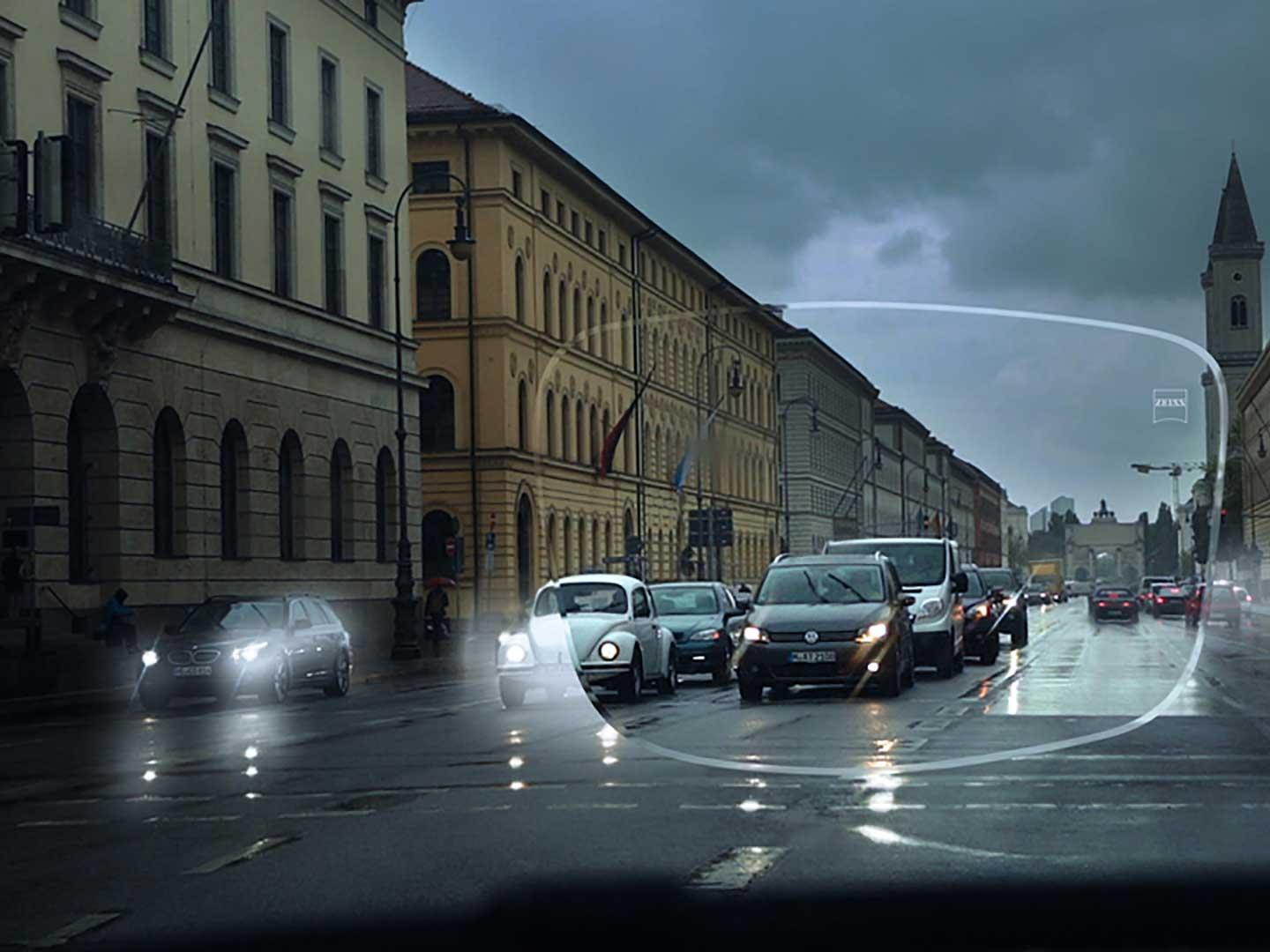 A képen rossz látási és fényviszonyok láthatók egy utcán. A nézőpont egy autó belseje egy szemüveglencsén keresztül nézve. 