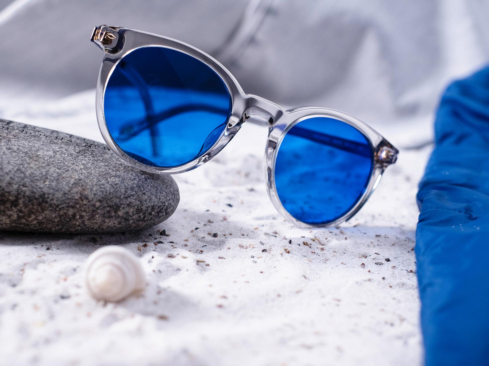 Egy kőnek támasztott, kék színezéssel ellátott napszemüveget ábrázoló kép