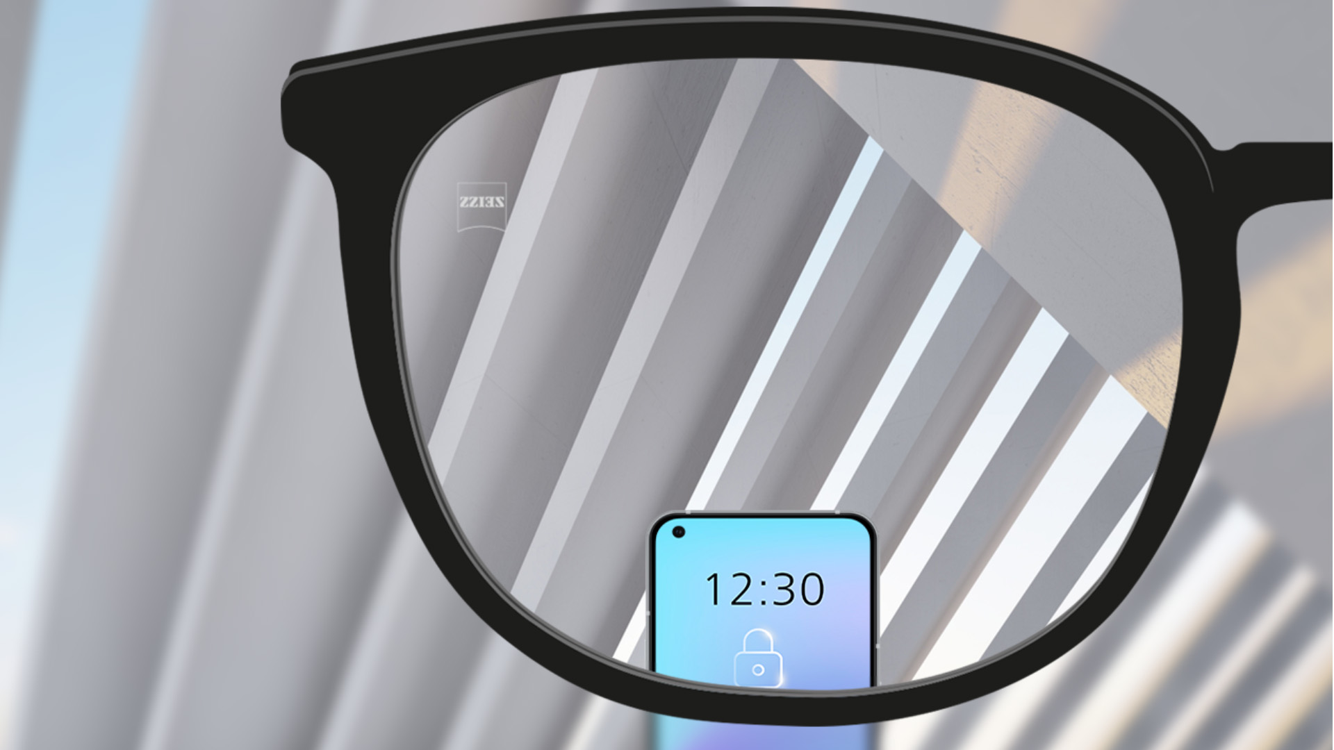 Személyes nézőpontból készült kép egy ZEISS SmartLife egyfókuszú szemüveglencséről, amelyen keresztül élesen látszik egy okostelefon és a szemüveglencse többi része.