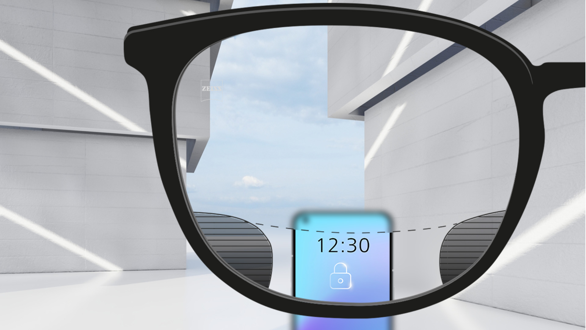 Személyes nézőpontból készült kép egy ZEISS Digital SmartLife szemüveglencséről, amelyen keresztül élesen látszik egy okostelefon és a lencse felső és alsó része; a lencse bal és jobb oldalán pedig apró homályos részek látszanak.