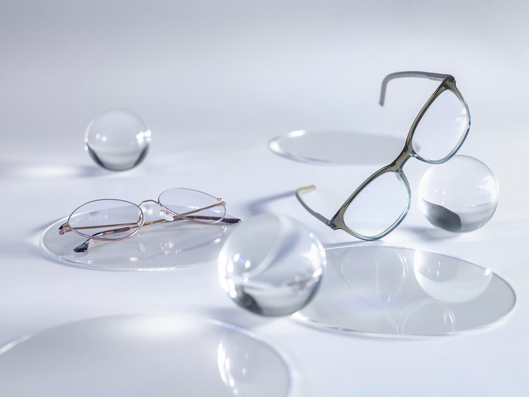 DuraVision® Silver rétegzéssel rendelkező lencsékkel ellátott szemüvegek, amelyeken nem látható tükröződés, ellentétben az őket körülvevő üveggolyókkal.
