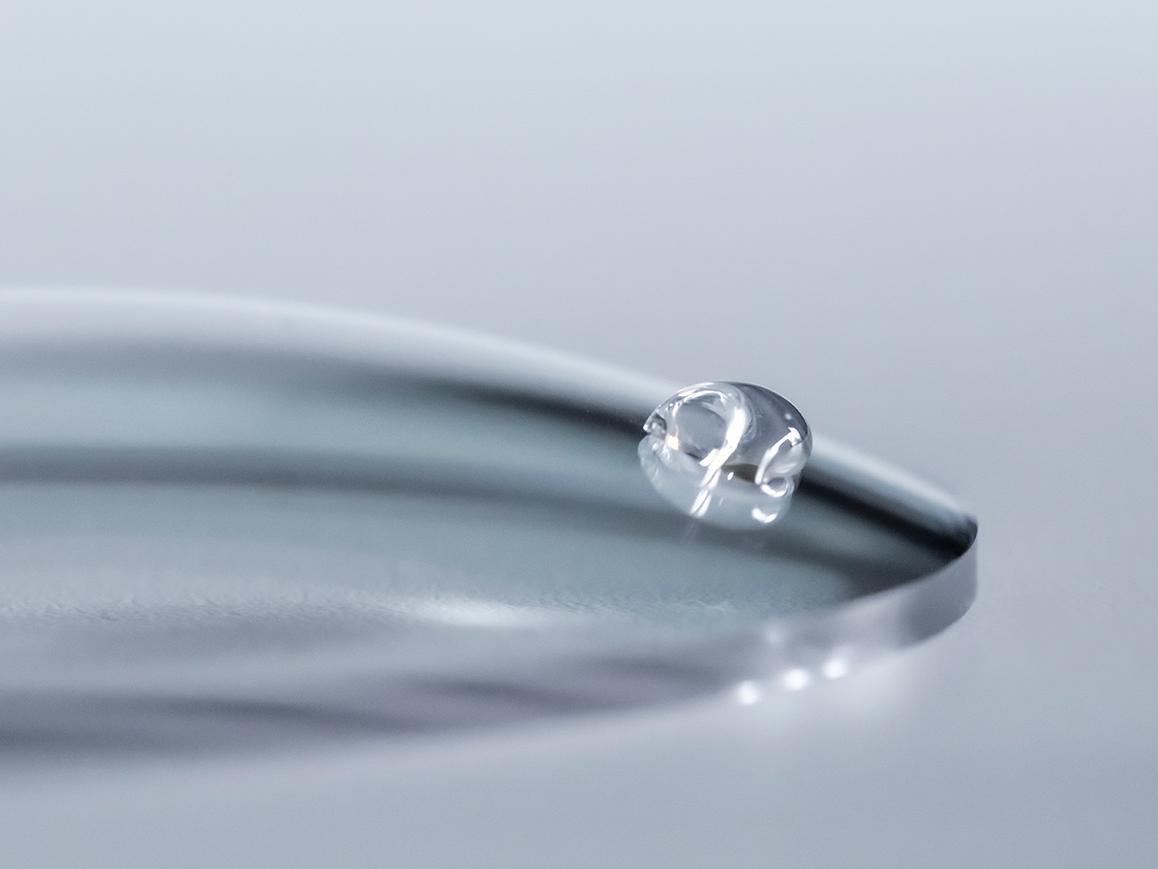 Egy vízcsepp legurul a tiszta rétegzéssel ellátott ZEISS lencséről.