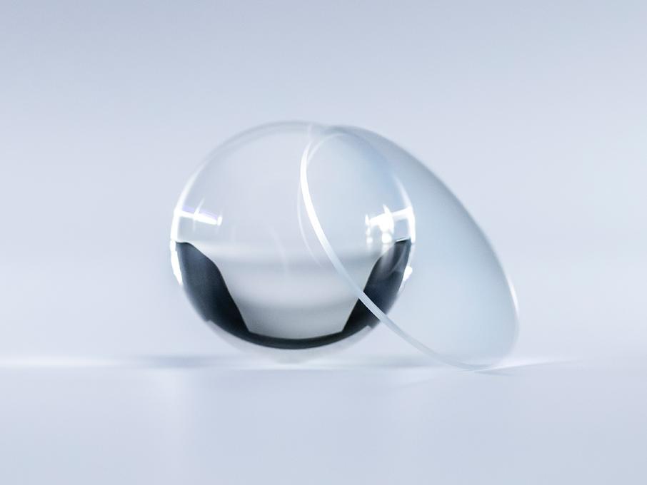 A ZEISS DuraVision Platinum felületkezeléssel ellátott lencse kristálytiszta, tükröződések nélkül, ellentétben a mellette lévő üveggolyóval.