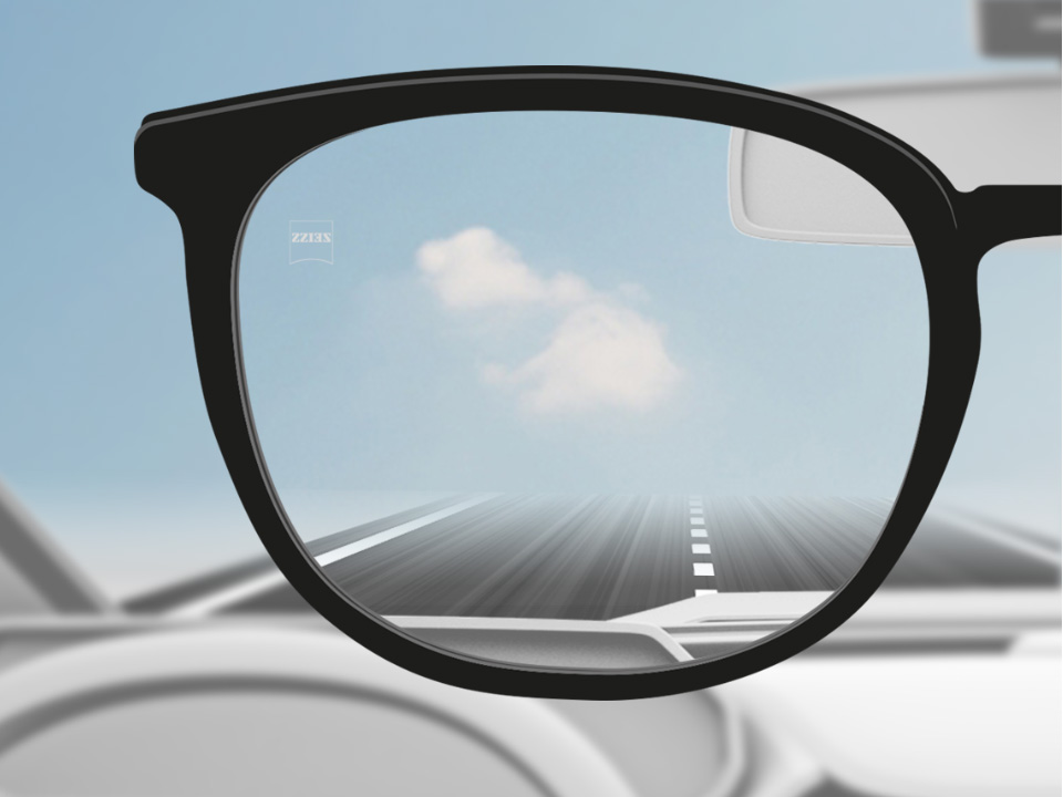 Egy autóvezető saját szemszögéből készült kép egy ZEISS DriveSafe egyfókuszú szemüveglencséről, amelyen keresztül élesen látszik a háttér. 
