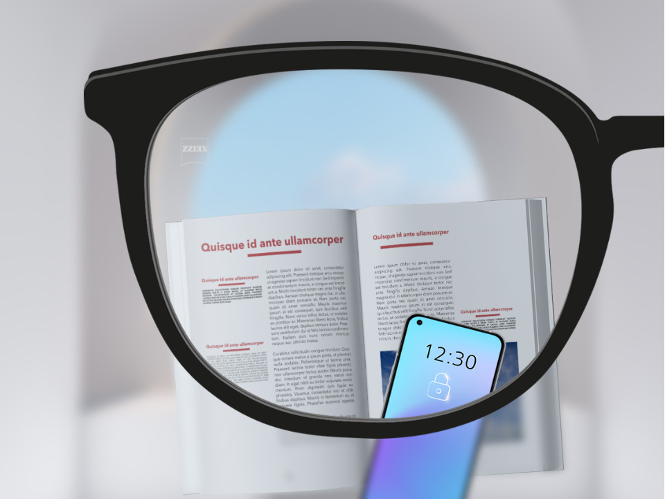 Saját szemszögből készült kép egy ZEISS SmartLife egyfókuszú szemüveglencséről, amelyen keresztül élesen látszik egy okostelefon és egy könyv, valamint a szemüveglencse többi része.