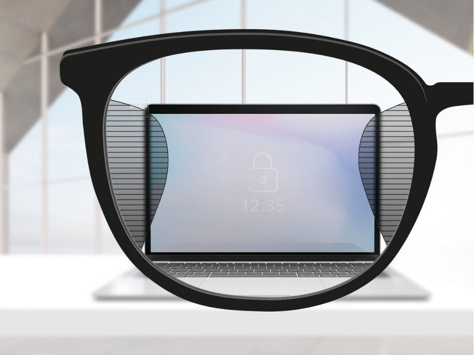 Saját szemszögből készült kép egy ZEISS Officelens szemüveglencséről, amelynek közepén egy számítógép képernyője látszik, a lencse bal és jobb oldalán pedig apró homályos részek látszanak.