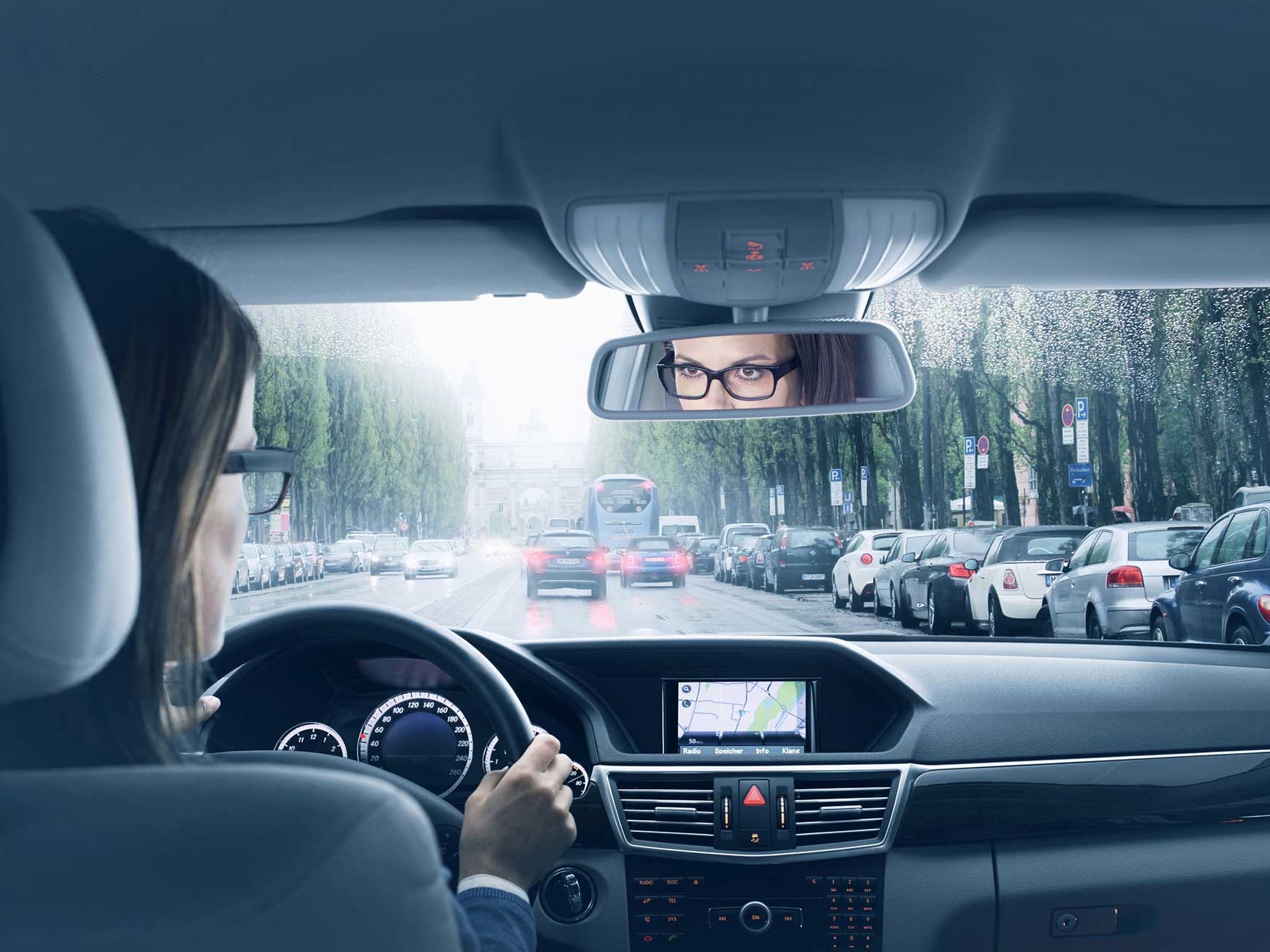 Egy autó belsejének képe, amelyben egy nő ül a volánnál. 