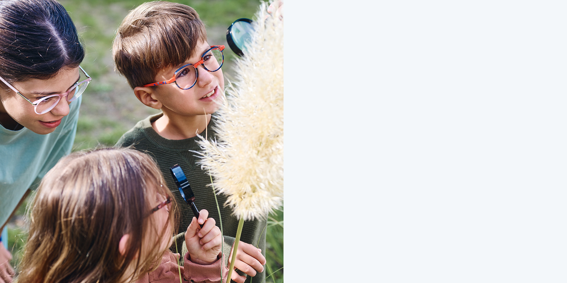 2 kislány és 1 kisfiú MyoCare szemüveglencsékkel. Egy növényt néznek, a három gyerek közül kettő nagyítóval nézi a növényt.