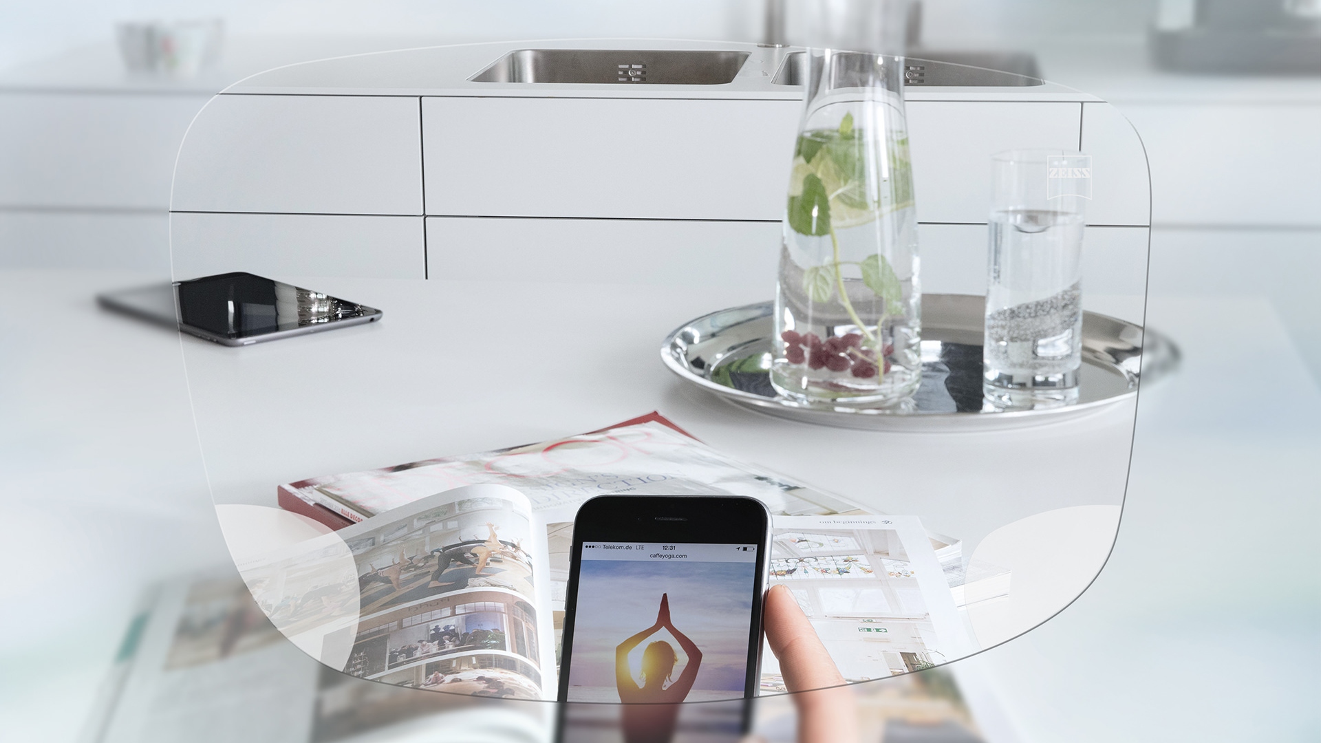 Egy okostelefon képernyője és egy rendezett konyhaasztal látványa a ZEISS EnergizeMe egyfókuszú szemüveglencsén keresztül